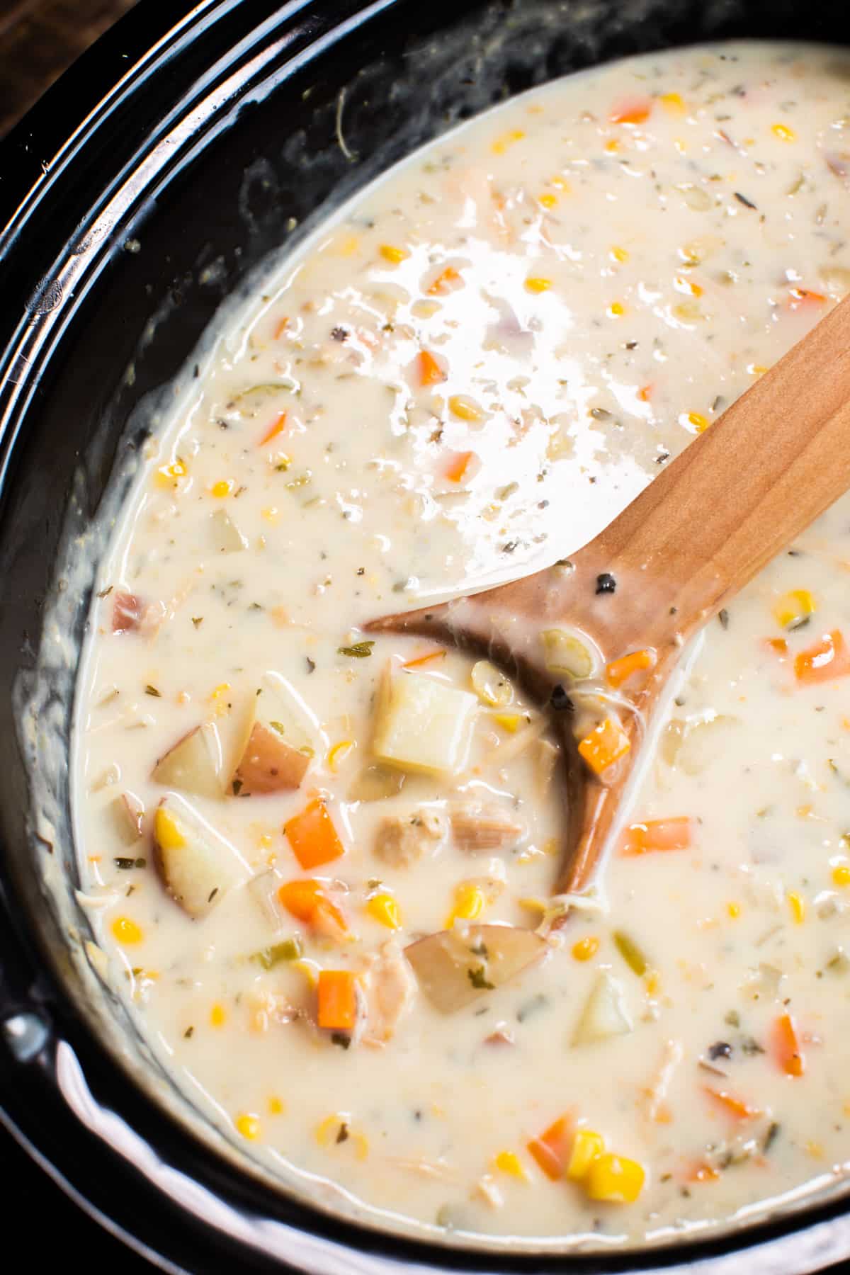 close up of turkey chowder on wooden spoon.