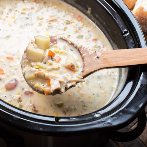 wooden spoon scooping turkey chowder out of slow cooker