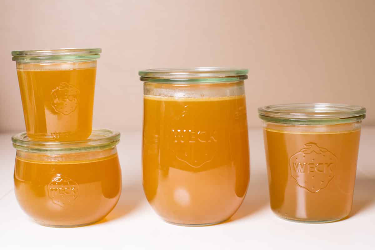 4 jars of turkey stock on a white table.