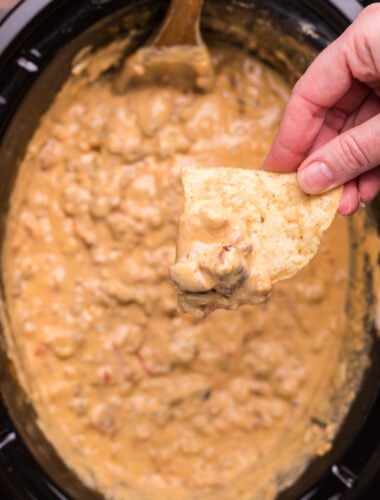 cheese burger dip in slow cooker with chip dipping from it