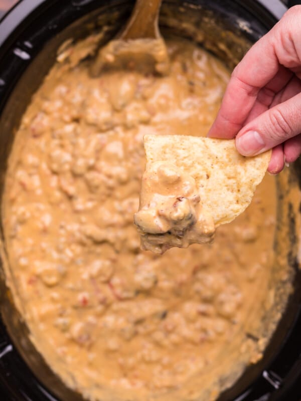 cheese burger dip in slow cooker with chip dipping from it