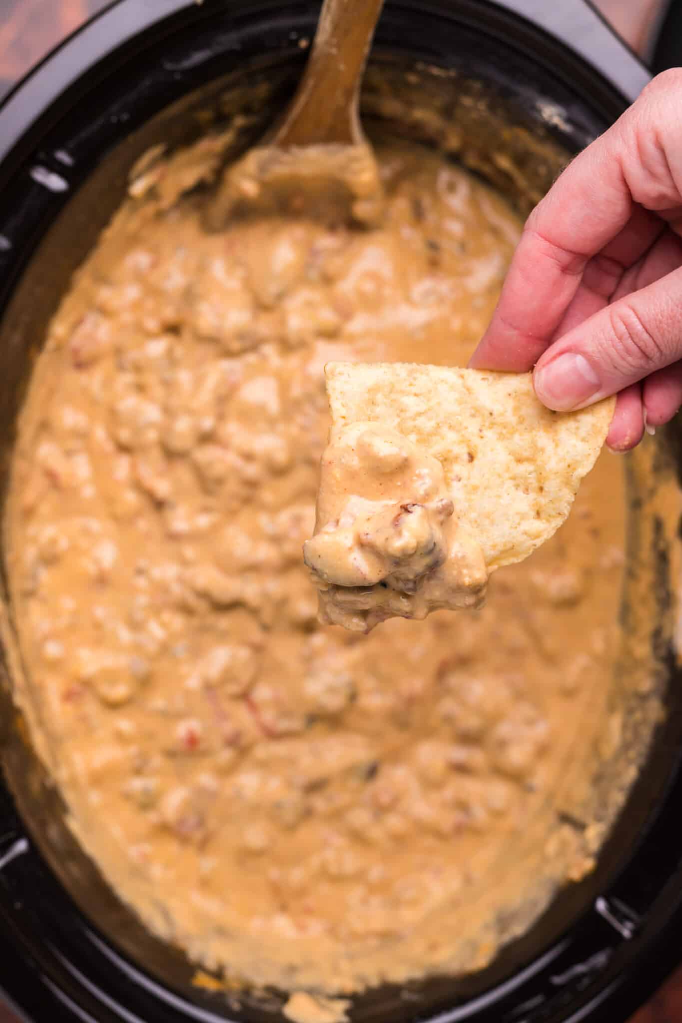 cheese burger dip in slow cooker with chip dipping from it
