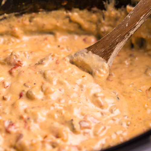 bacon cheeseburger dip with wooden spoon in it.