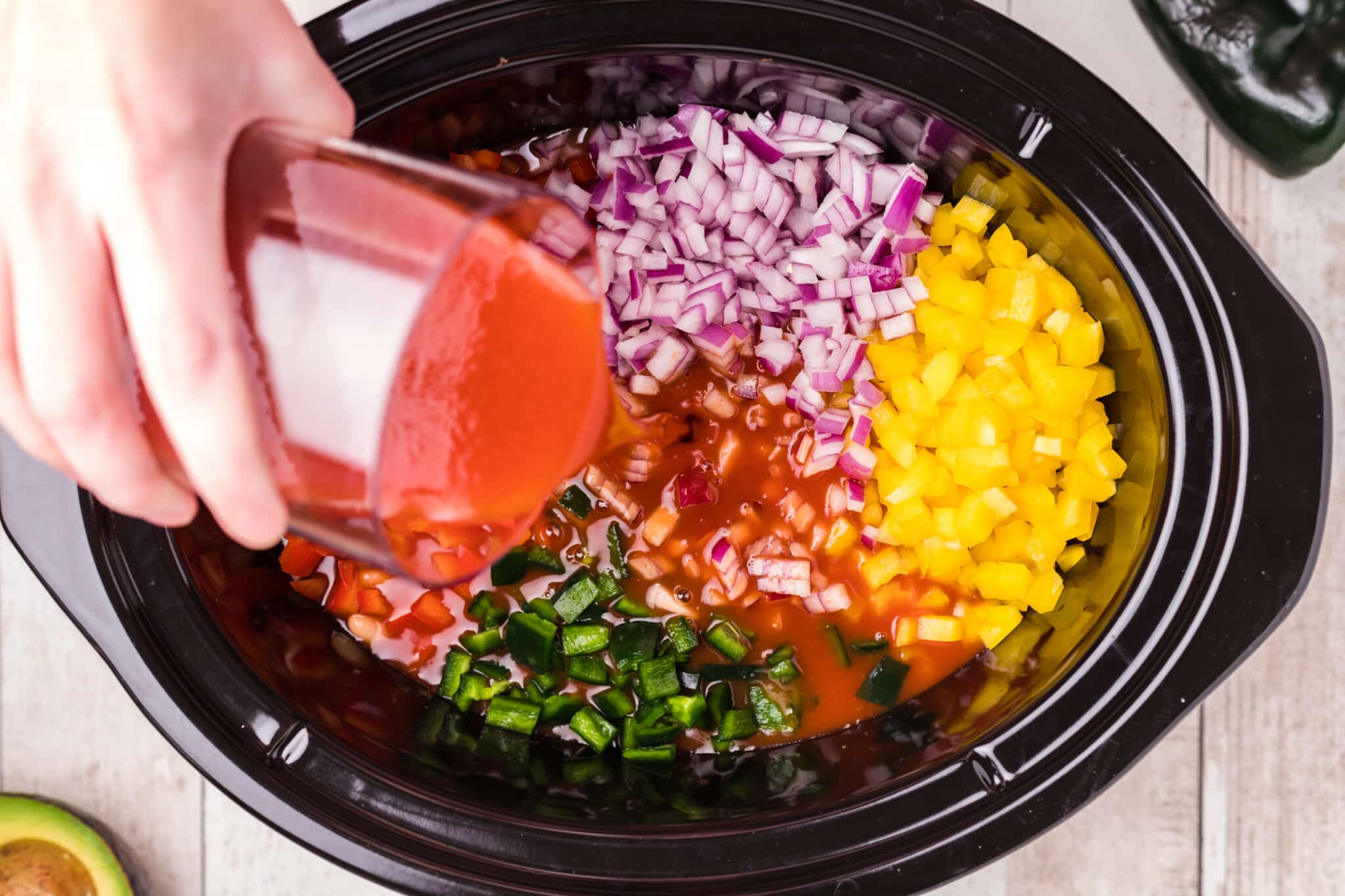 v8 juice being poured over vegetables in slow cooker