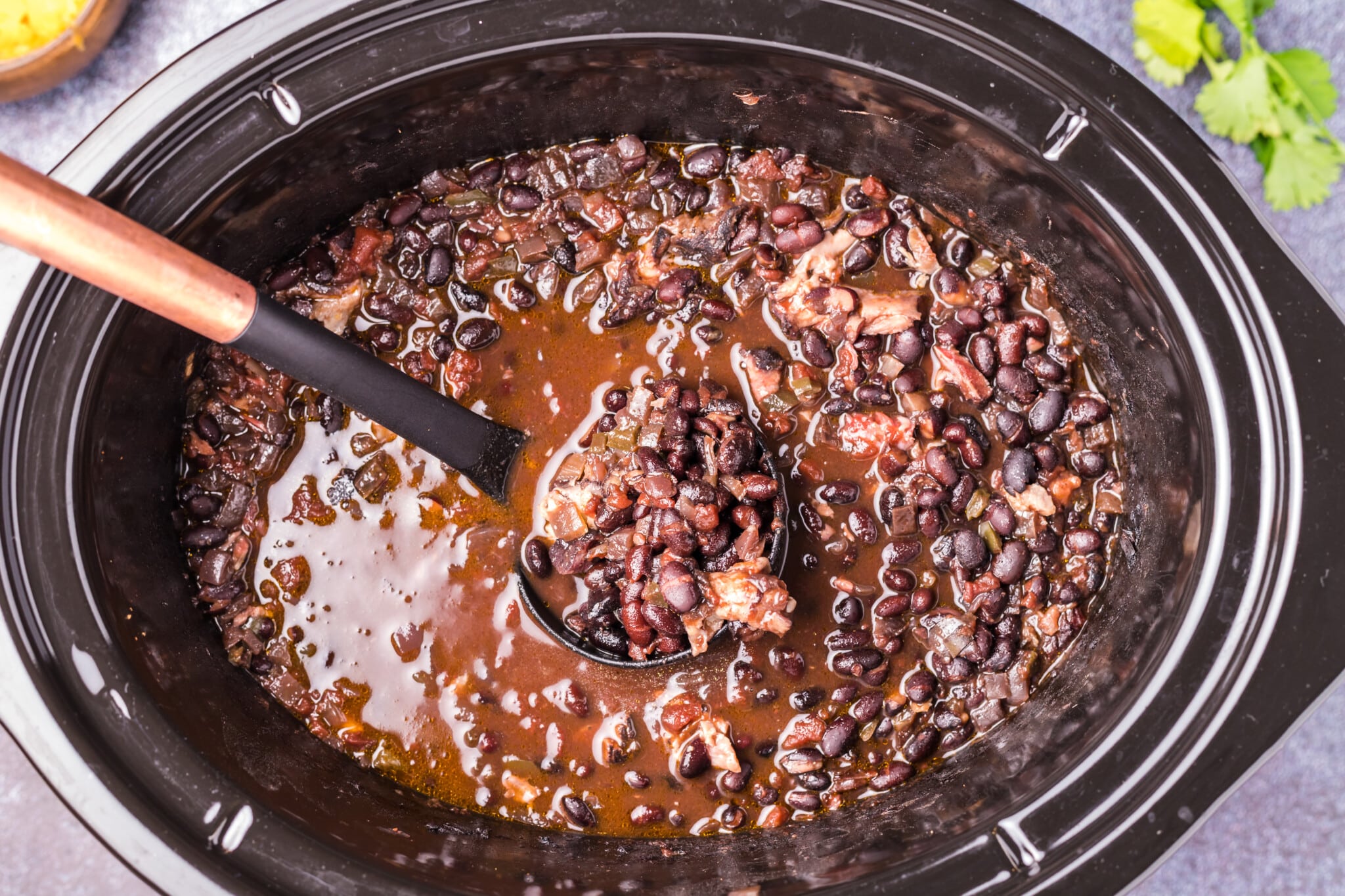 black bean soup on ladle in slow cooker