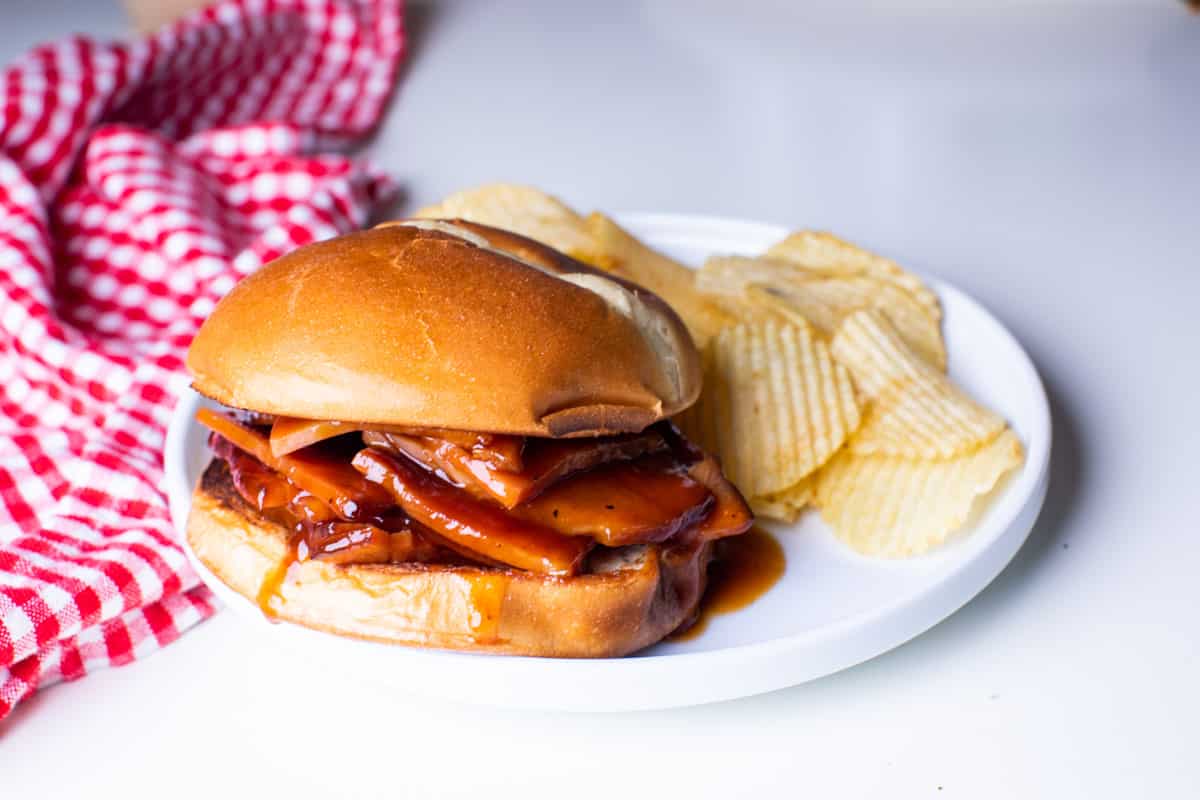 barbecue ham on bun with chips on side