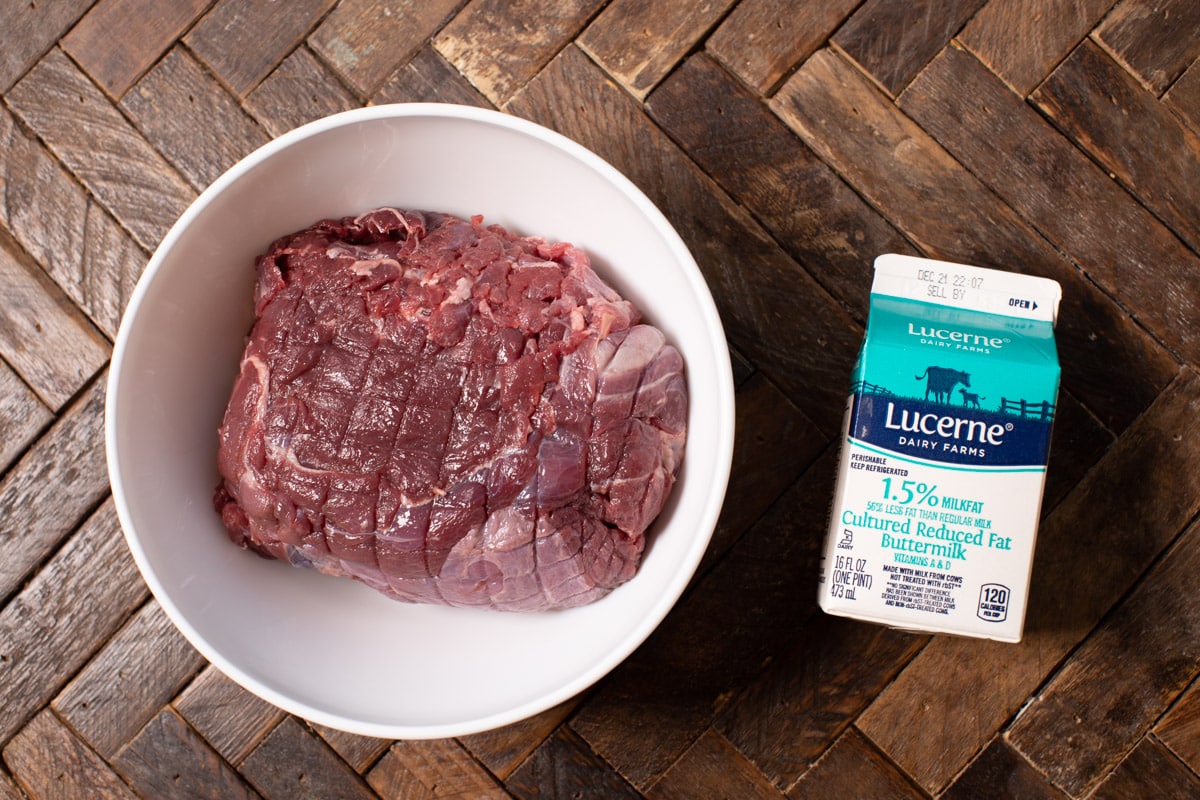 venison roast in bowl and carton of buttermilk next to it.
