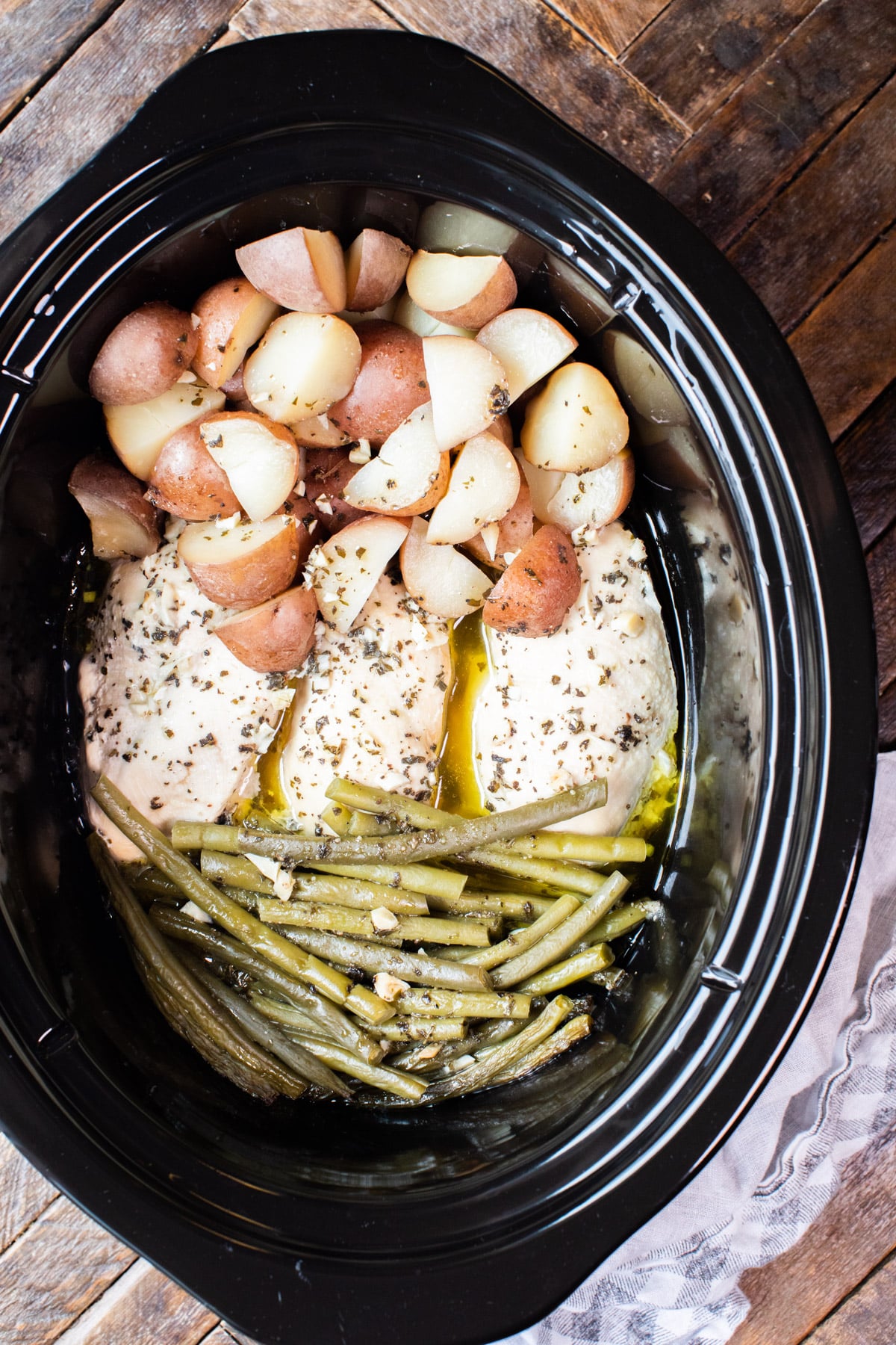 close up photo of chicken, potatoes and green beans in slow cooker