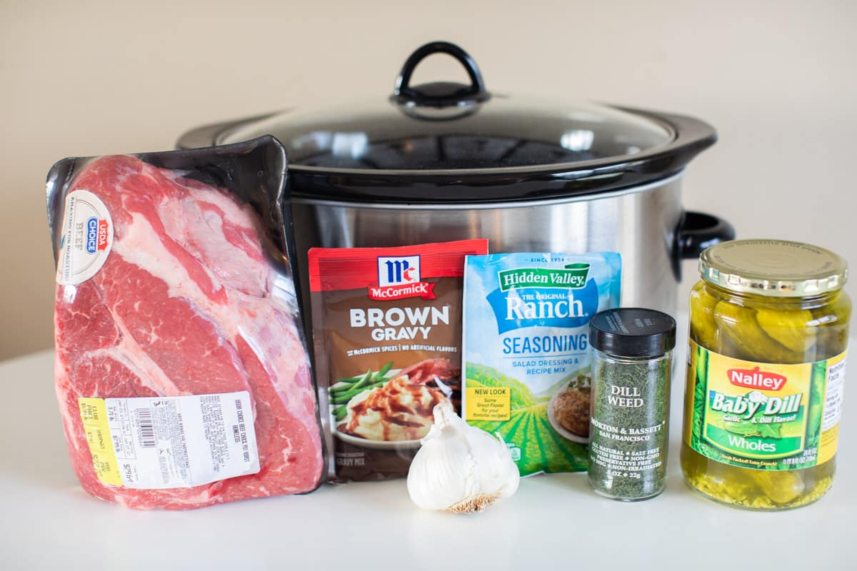 ingredients for dill pickle roast in front of a slow cooker