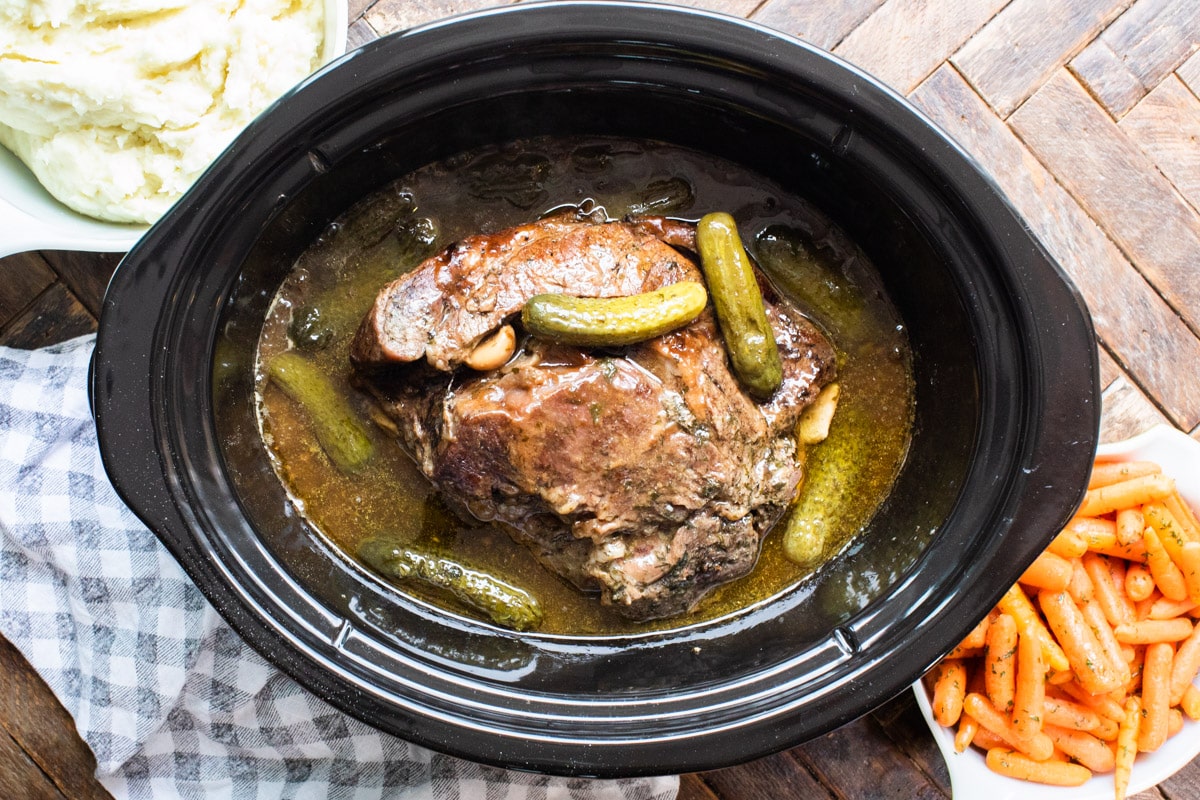 cooked dill pickle roast with mashed potatoes and carrots on the side