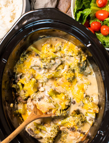 cheesy broccoli chicken in slow cooker with wooden spoon in it.