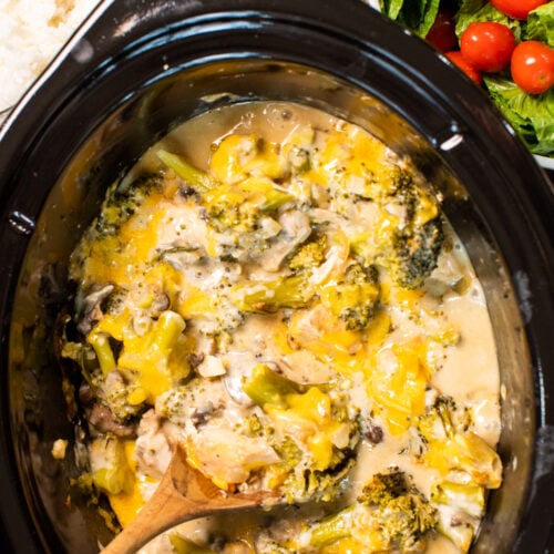 cheesy broccoli chicken in slow cooker with wooden spoon in it.