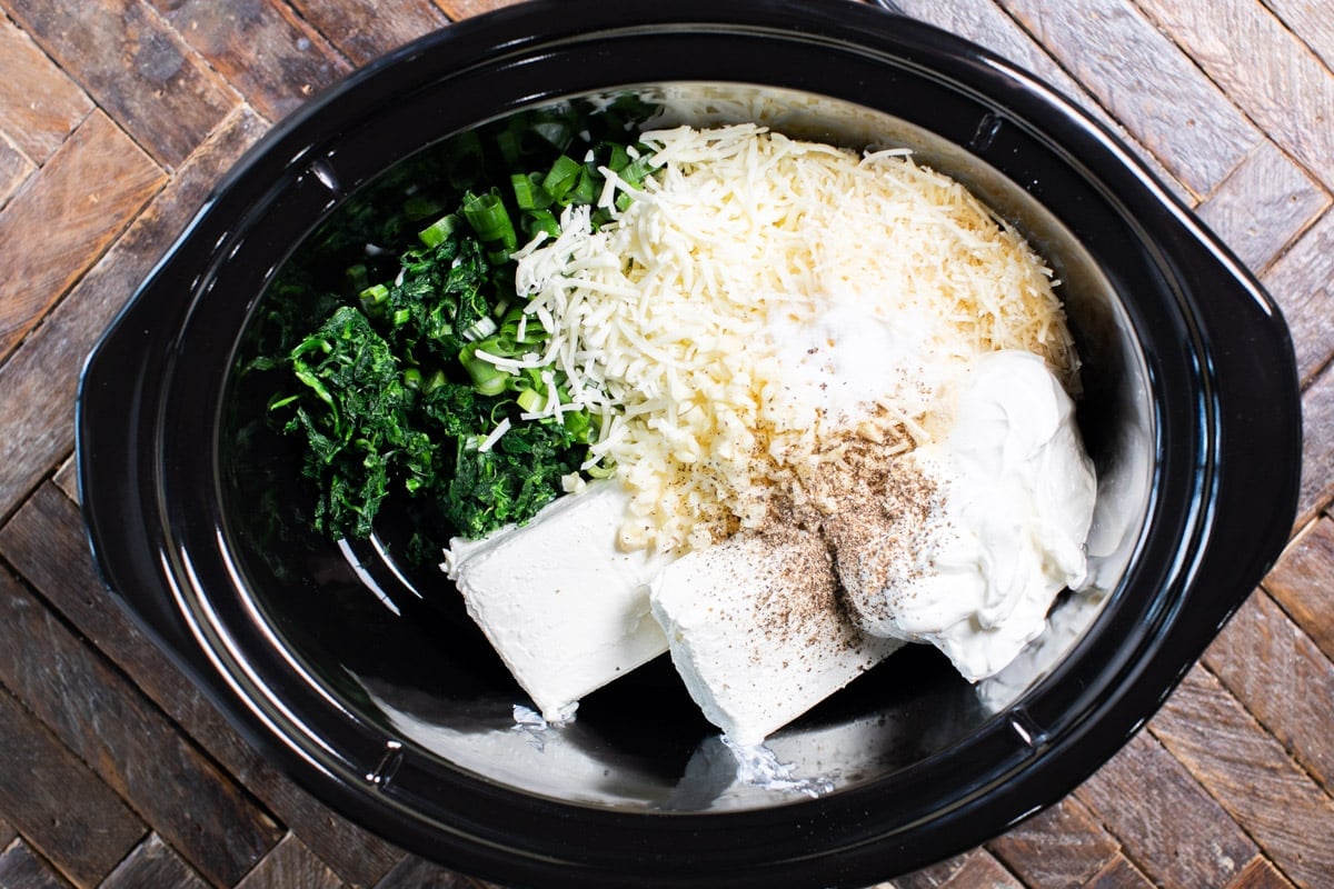 spinach dip ingredients in the slow cooker before stirring