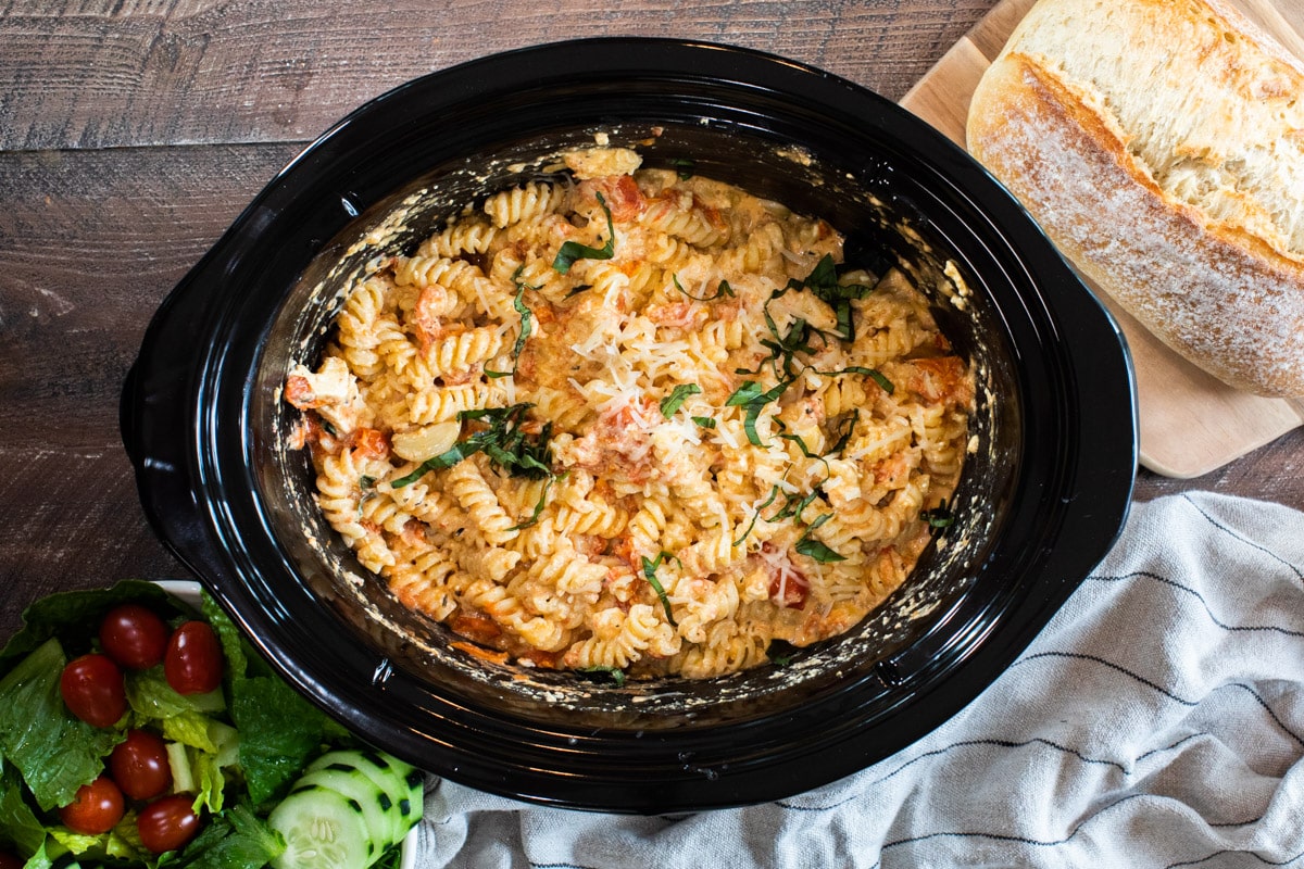 feta tomato pasta in the slow cooker with basil and parmesan cheese on top.