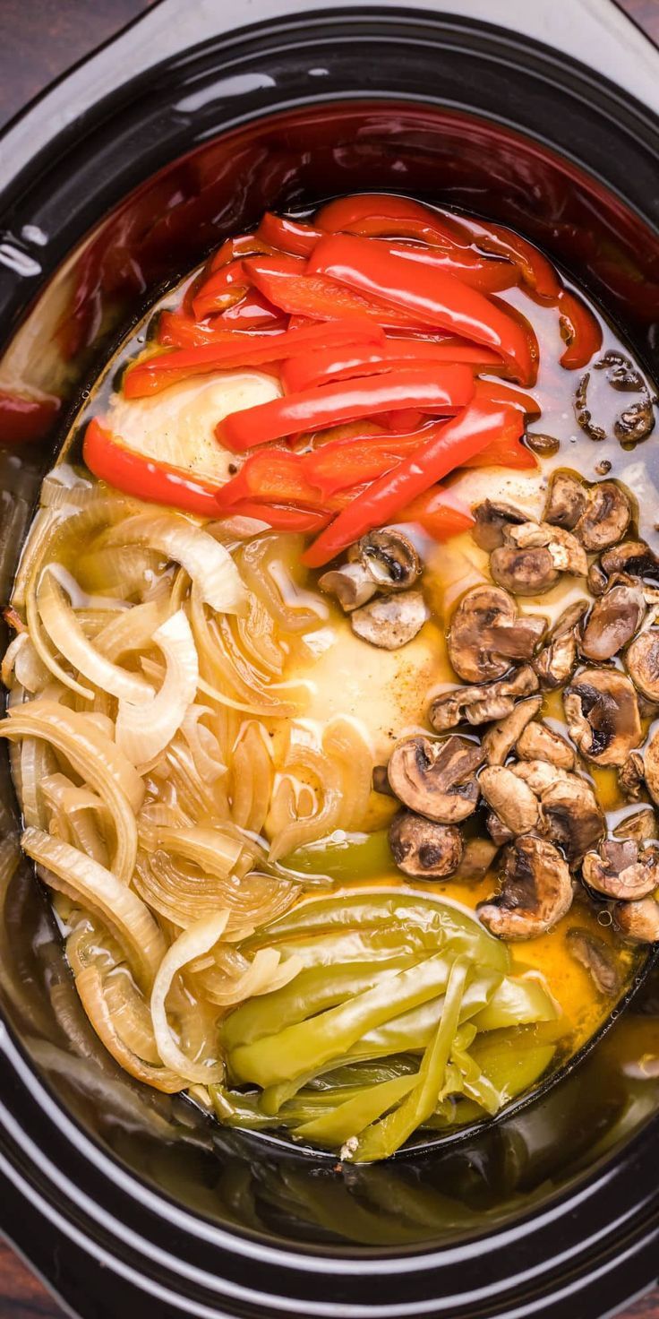 Chicken, peppers and onion in a slow cooker with mushrooms for philly cheese steaks.