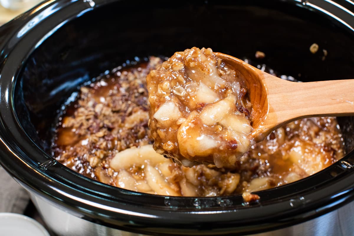 scoop of apple crisp coming from slow cooker