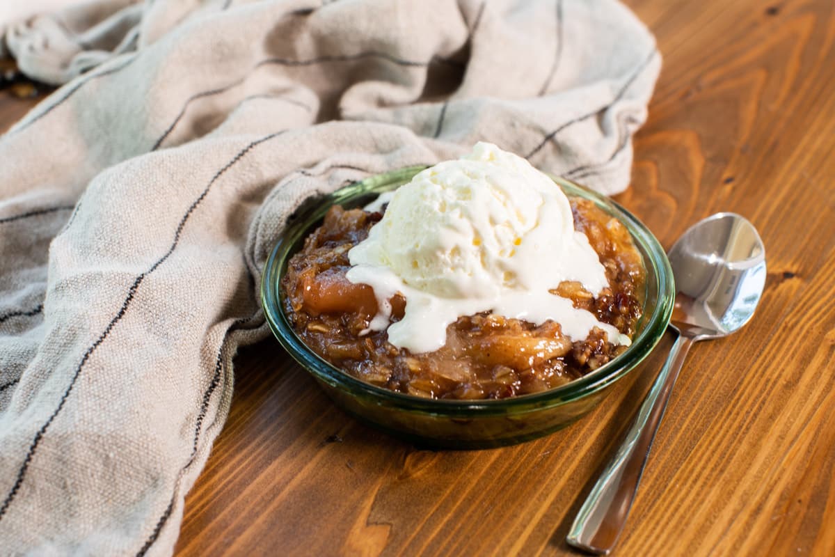 apple crisp in bowl with ice cream on top.