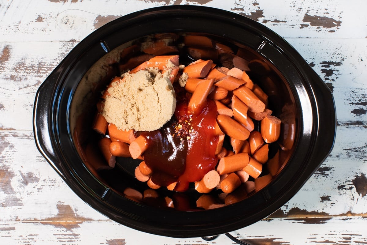 cut hot dogs in slow cooker with ketchup, barbecue sauce and brown sugar on top.