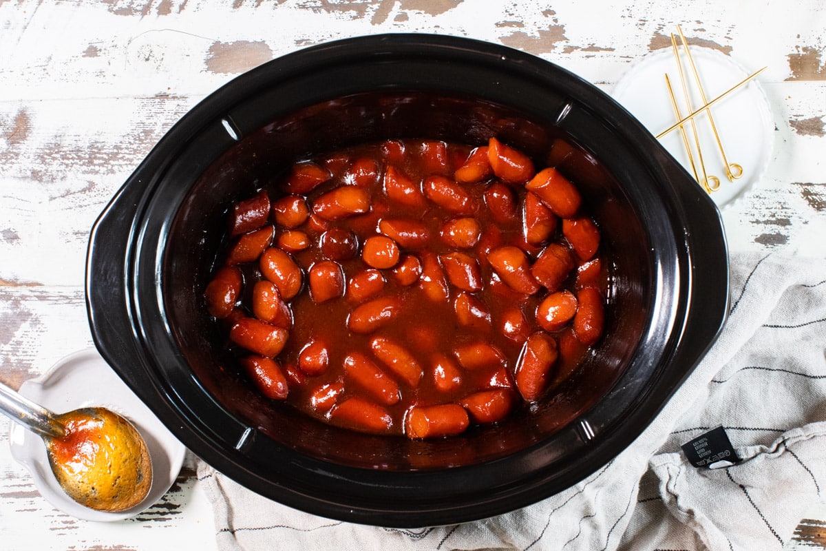 cooked bourbon hot dogs in slow cooker on white table