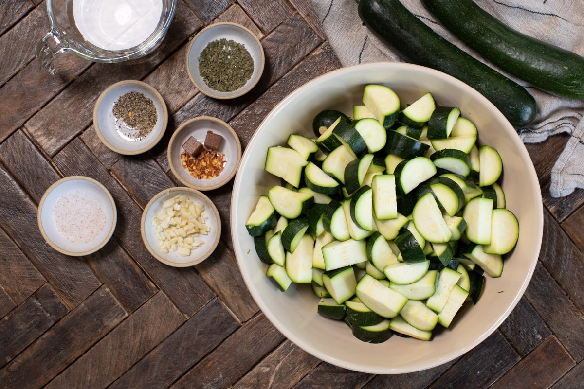 sliced zucchini in bowl with spices on the side