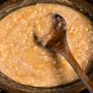 close up of banana jam in slow cooker with wooden spoon in it.