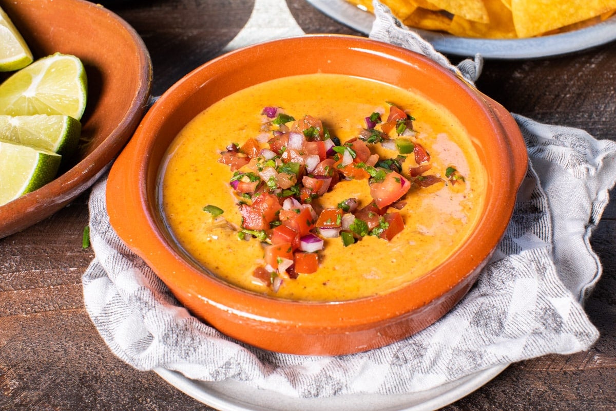 brown bowl with chili cheese dip in it with salsa on top.