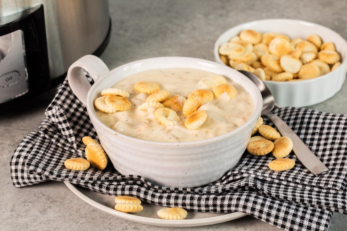 clam chowder in white bowl with oyster crackers on top