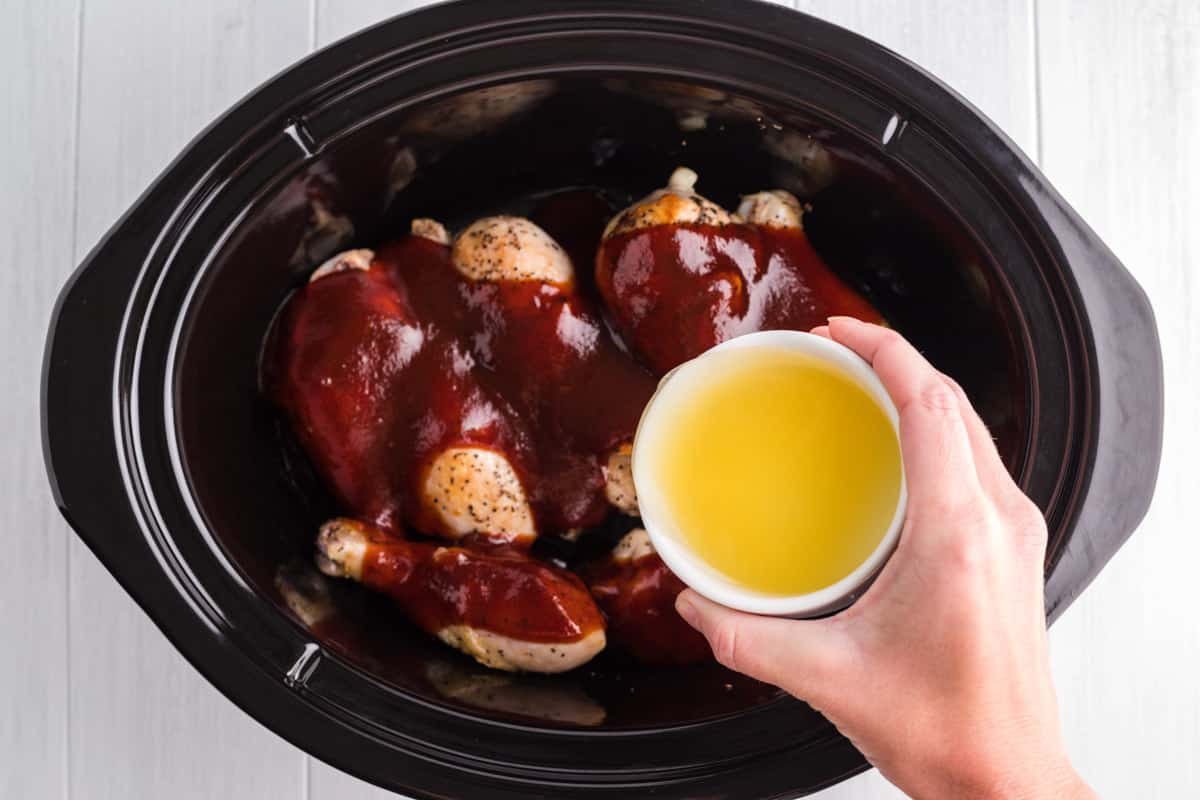 pineapple juice being poured over chicken in slow cooker