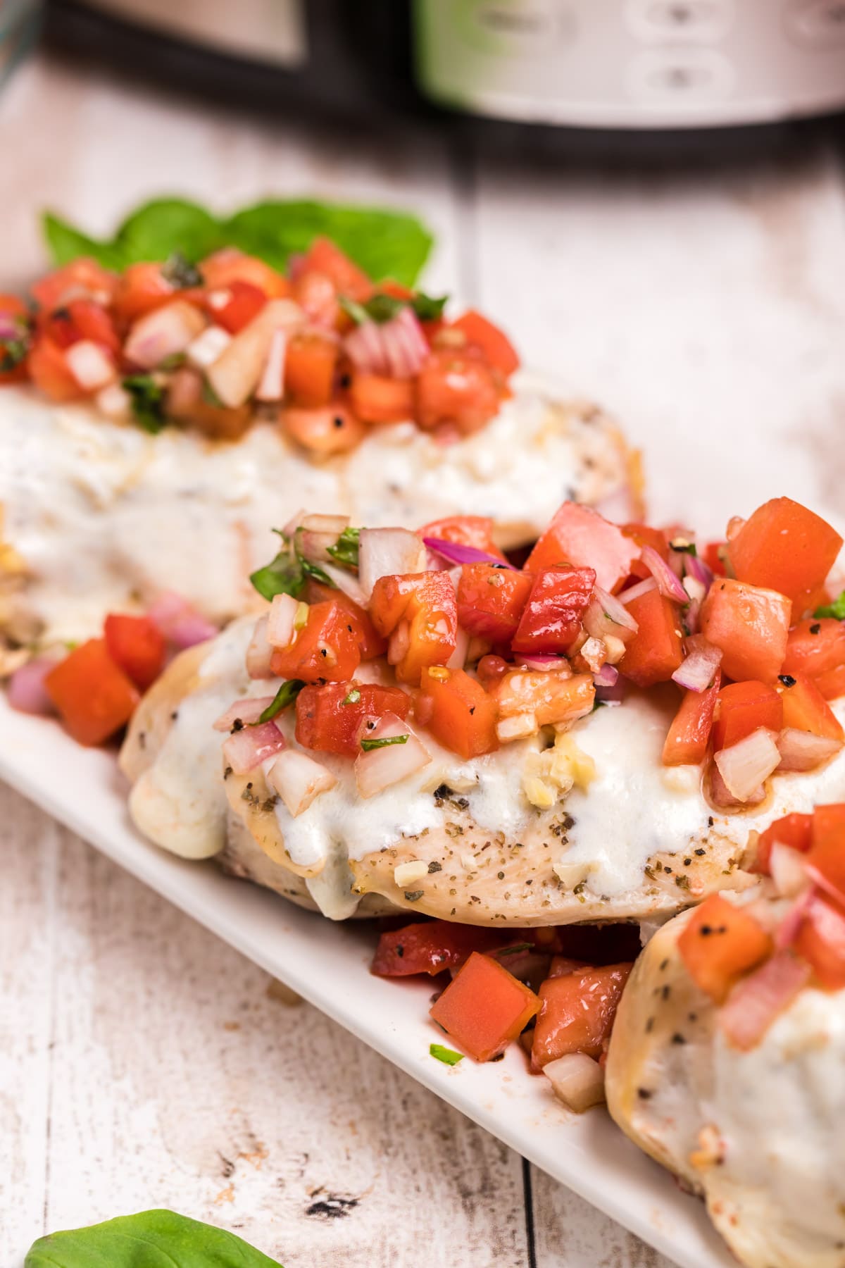 3 chicken breasts on a plate with bruschetta tomato topping and cheese