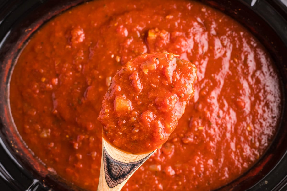 marinara sauce on a spoon coming from slow cooker