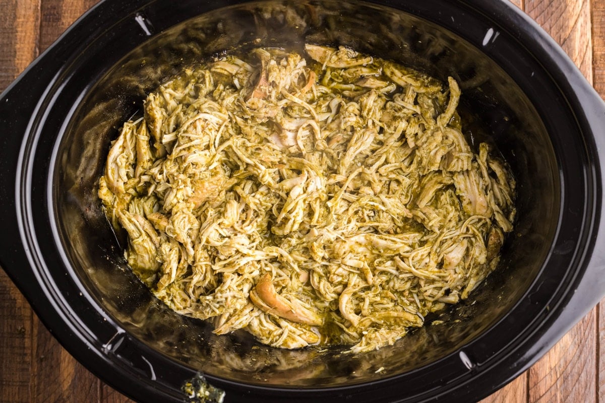 shredded pesto chicken in a slow cooker.