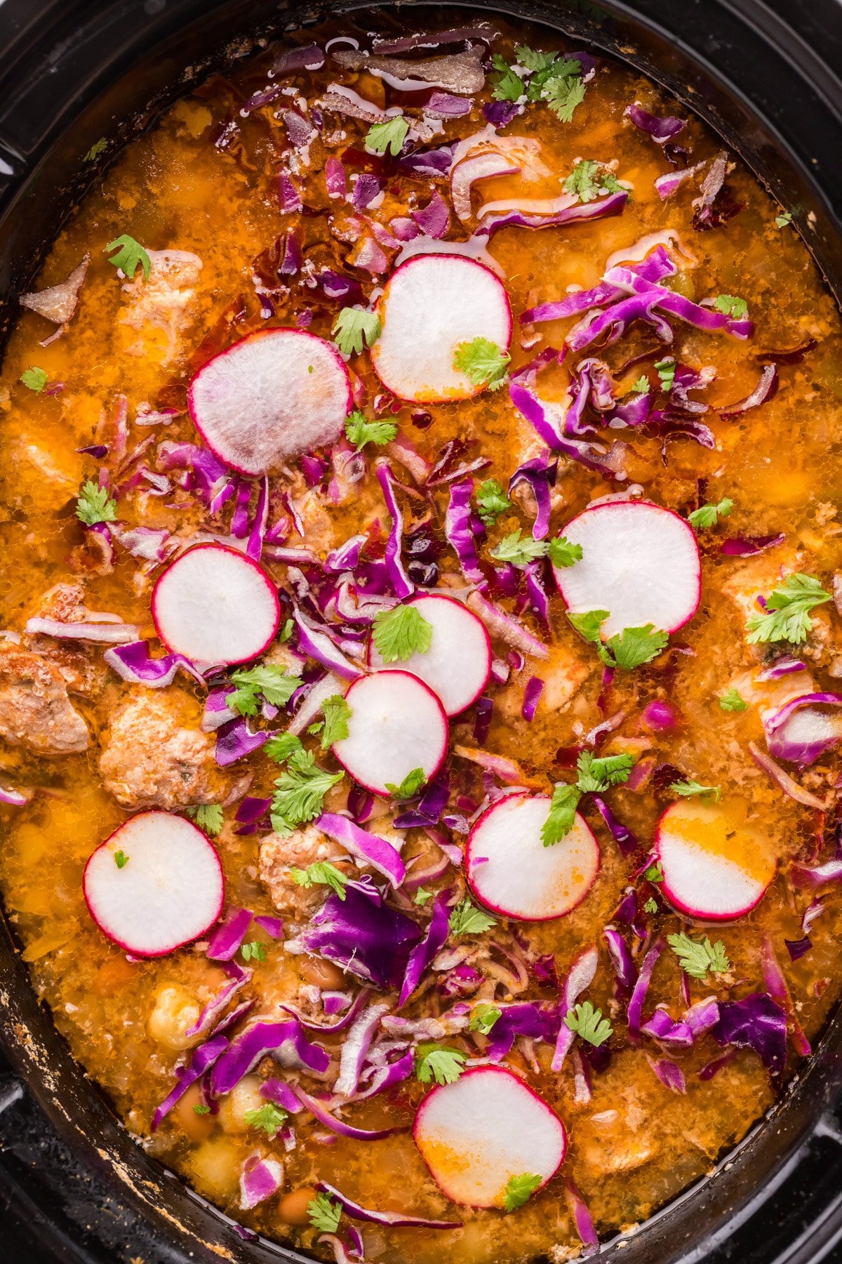 pozole in slow cooker with radish on top