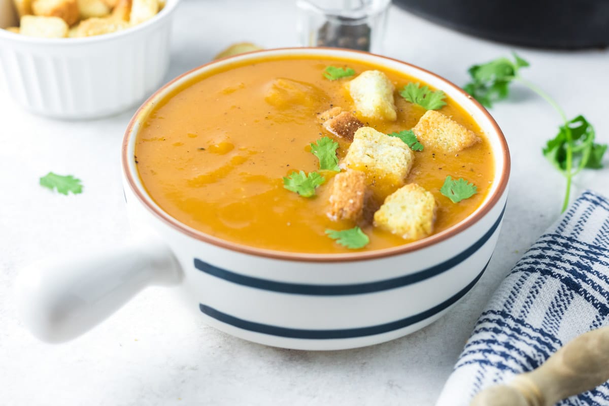 white and blue bowl with butternut squash soup in it.