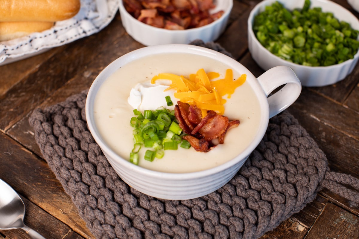 bowl of baked potato soup with sour cream, bacon, cheese and sour cream on top