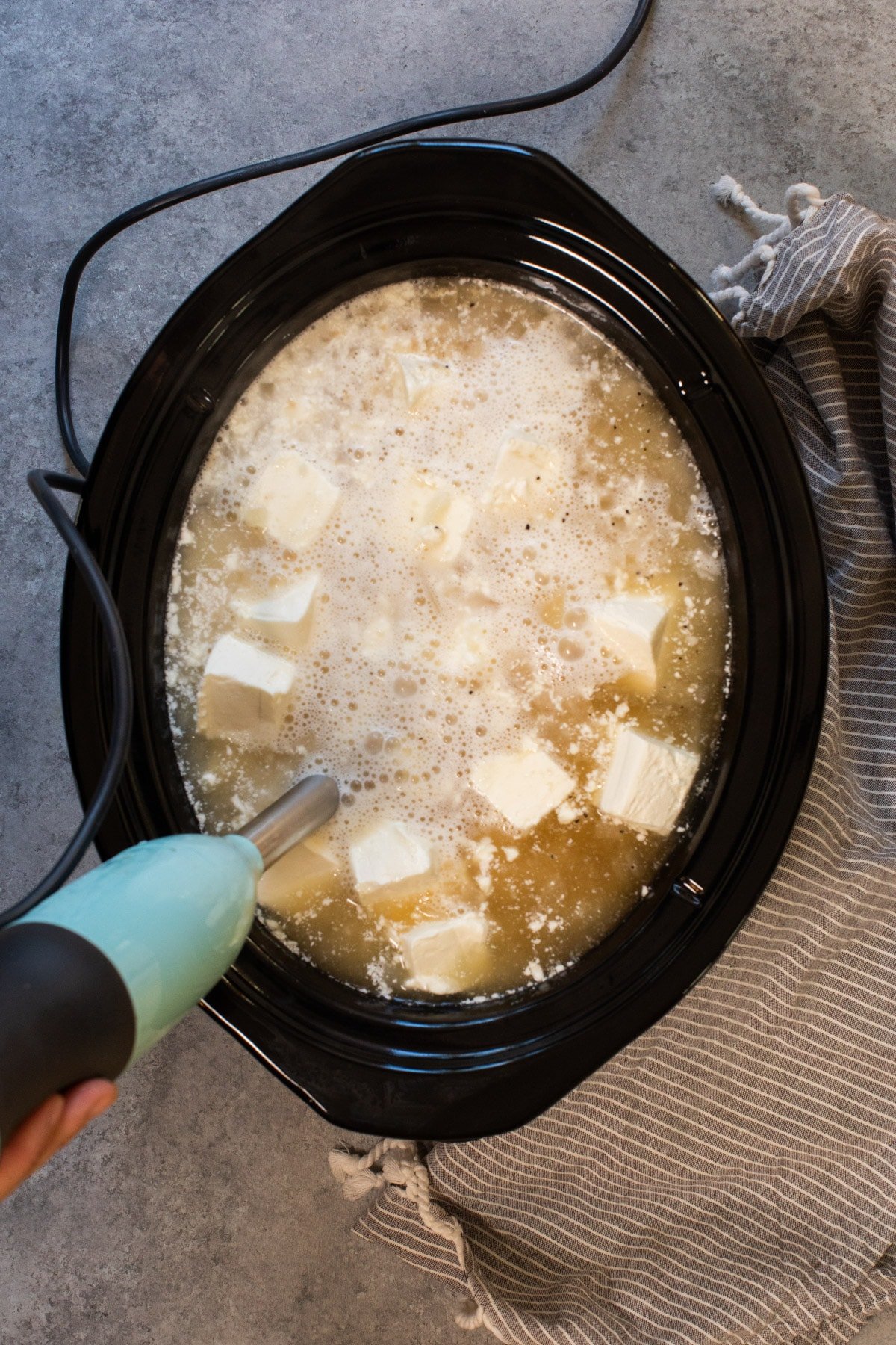cream cheese being added to the soup, being blended up.