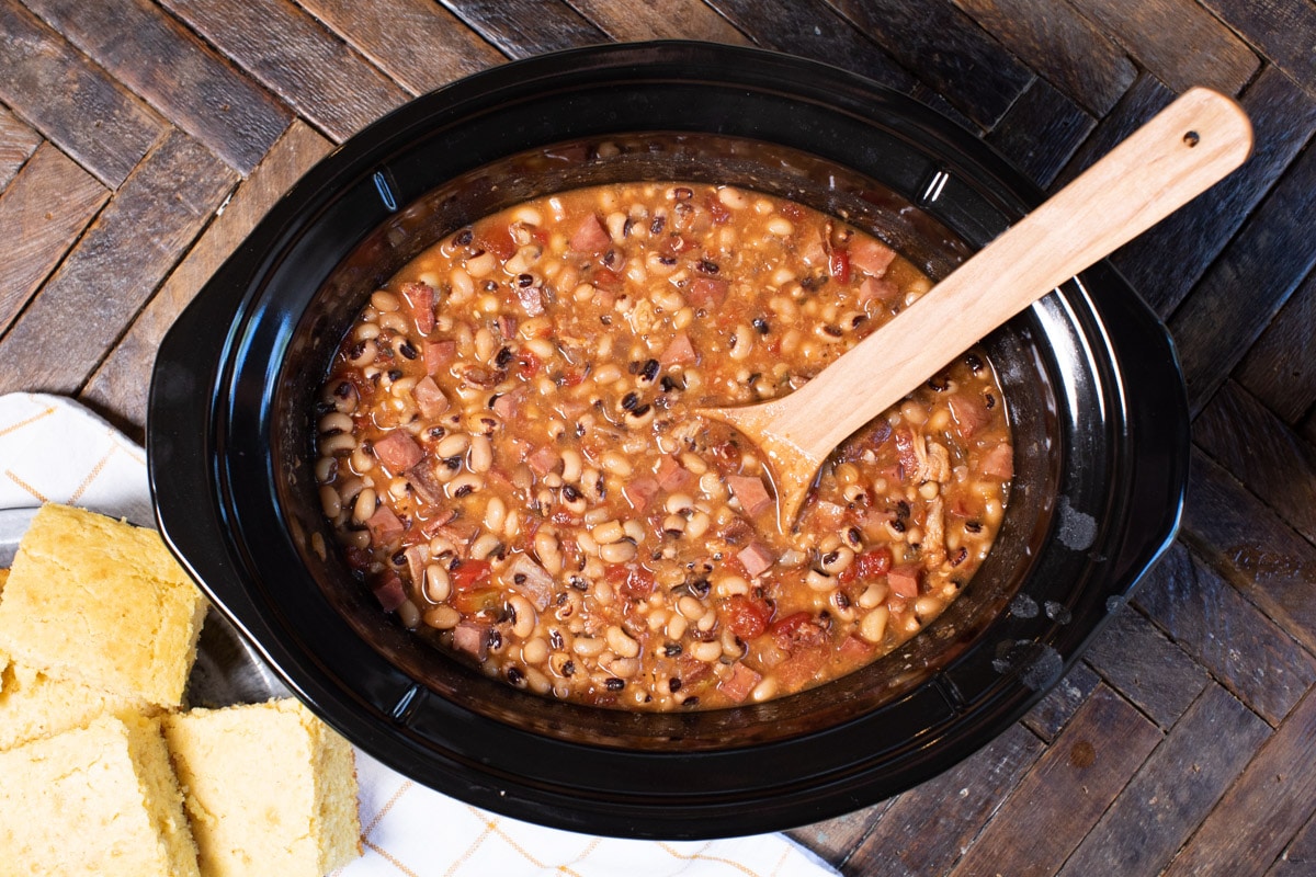 cooked black eyed peas in slow cooker with spoon in it.