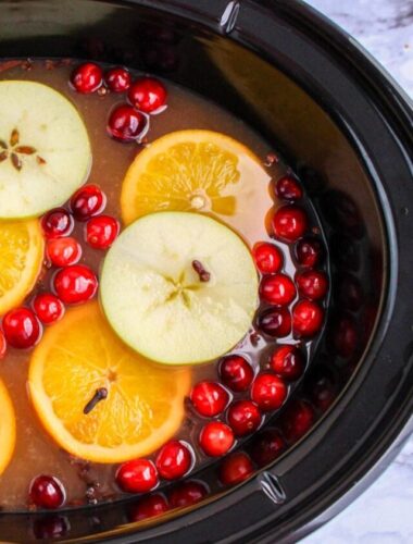 Crockpot full of wassail drink with fruit.