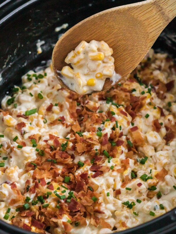 creamed corn in crockpot with wooden spoon.