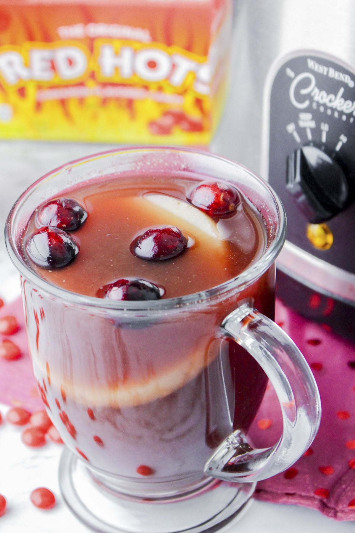 Mug of red hot cider (punch) in front of slow cooker