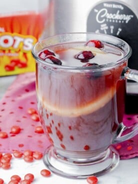 mug of red hots punch in front of slow cooker