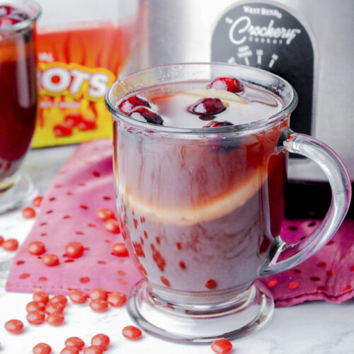 mug of red hots punch in front of slow cooker