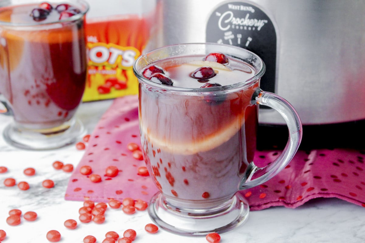 mug of red hots punch in front of slow cooker