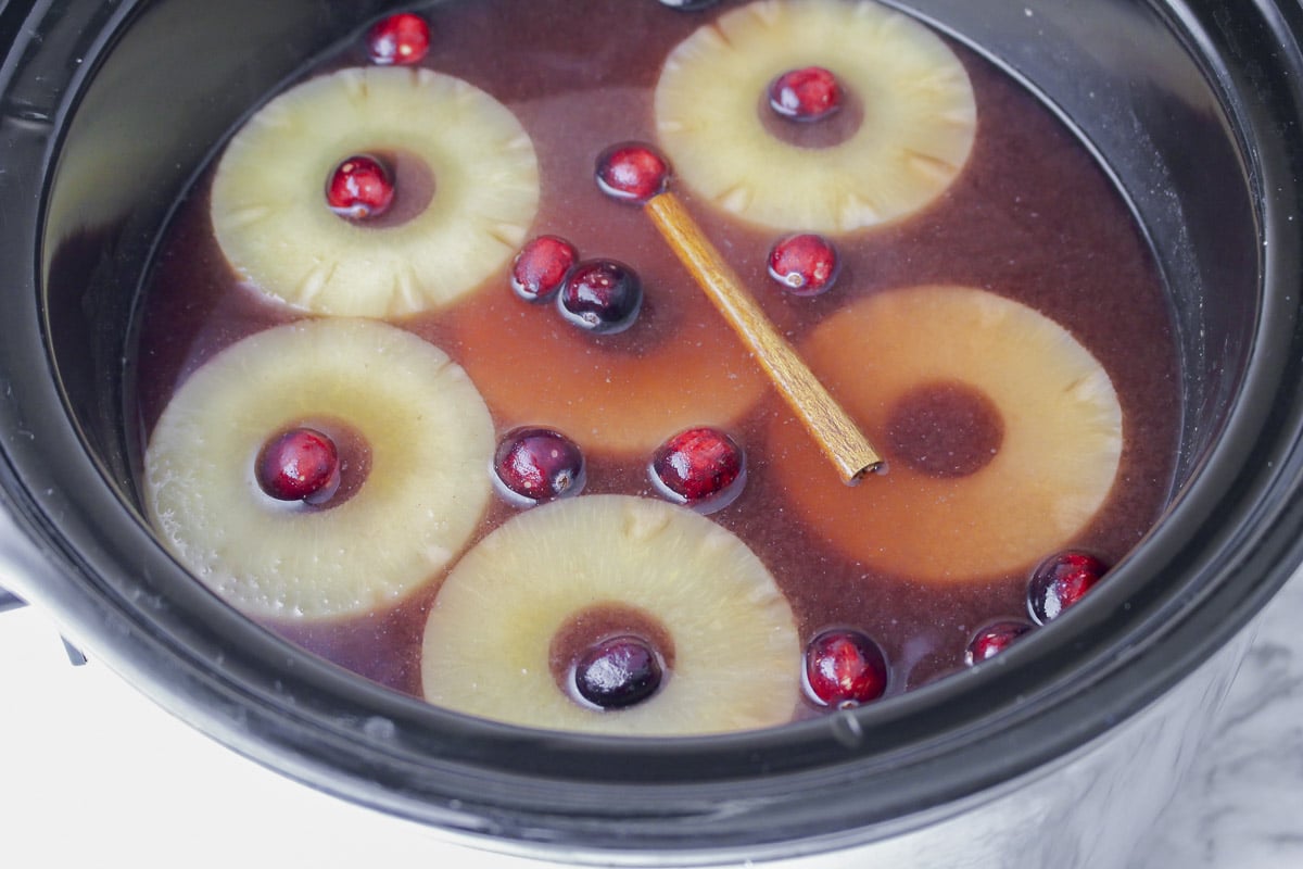 slow cooker with red hot punch, pineapple and cinnamon sticks