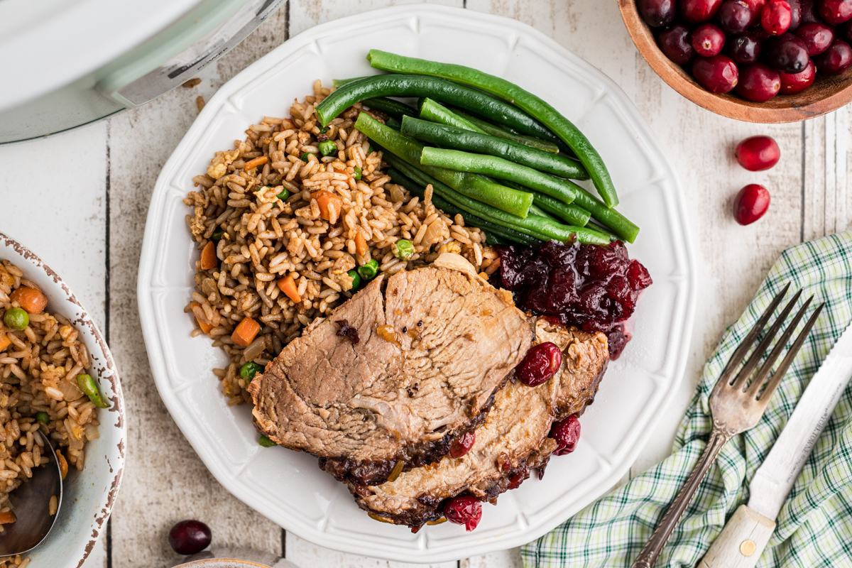 Plate of wild rice, pork loin, cranberry sauce and green beans.