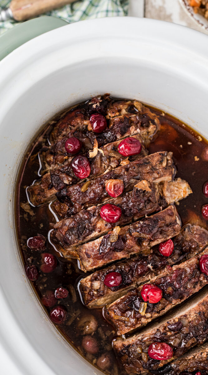 Long image of cranberry pork loin with fresh cranberries on top.