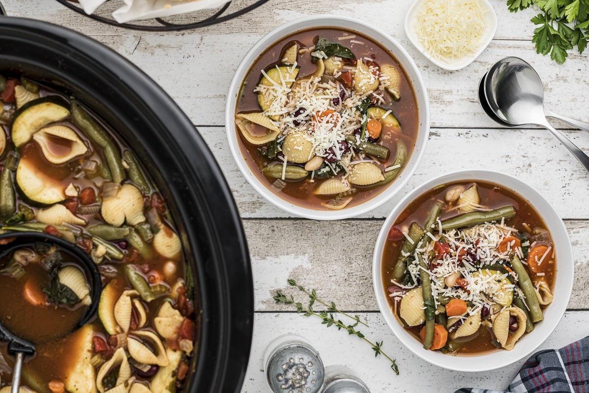 overhead shot of minestrone soup in slow cooker and 2 bowls