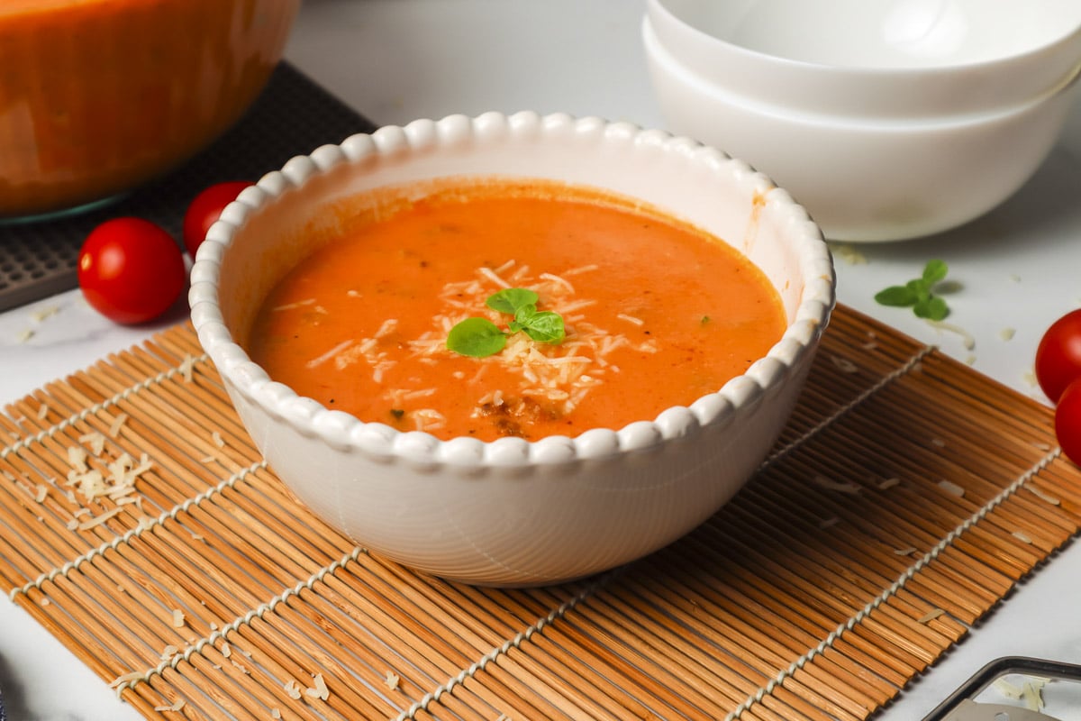 bowl of tomato soup with basil leaves on top