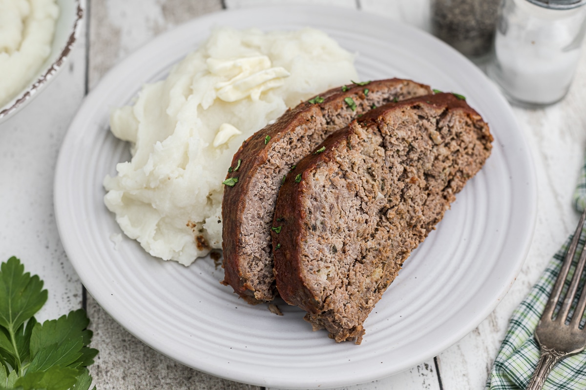sliced meatloaf on plate with mashed potatoes