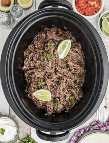 mexican shredded beef in slow cooker with limes.