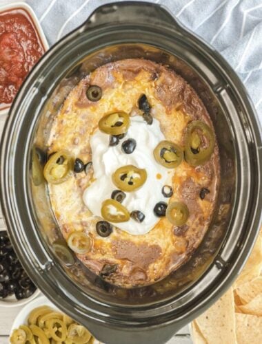 Cooked texas trash dip in the slow cooker with olives and jalapenos.